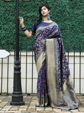 Woman in navy floral saree with gold border, standing by lamp post, elegant traditional wear