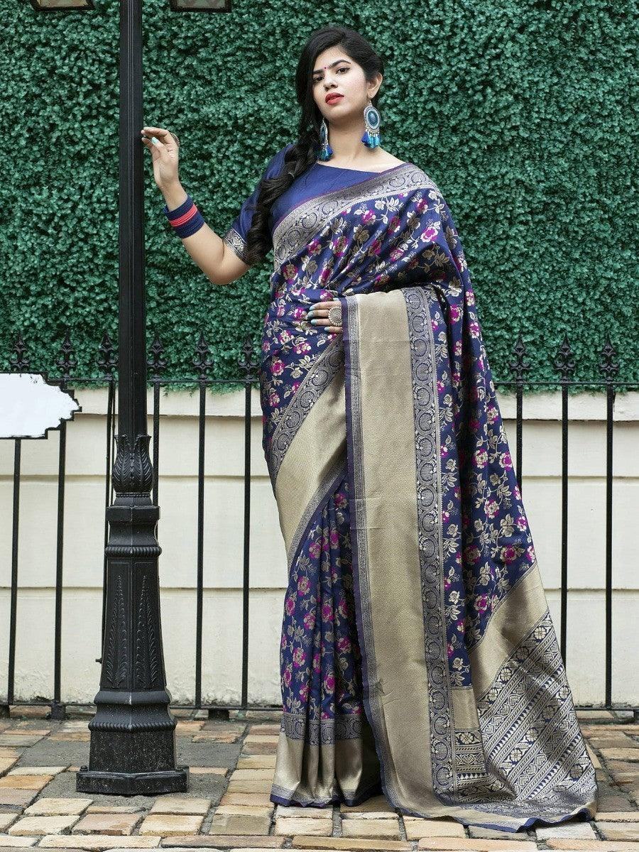 Woman in navy floral saree with gold border, standing by lamp post, elegant traditional wear
