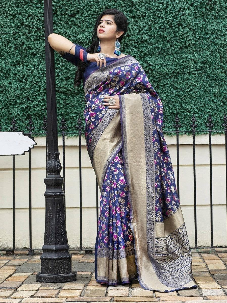 Woman in navy floral saree with gold border, standing by lamp post, elegant traditional wear