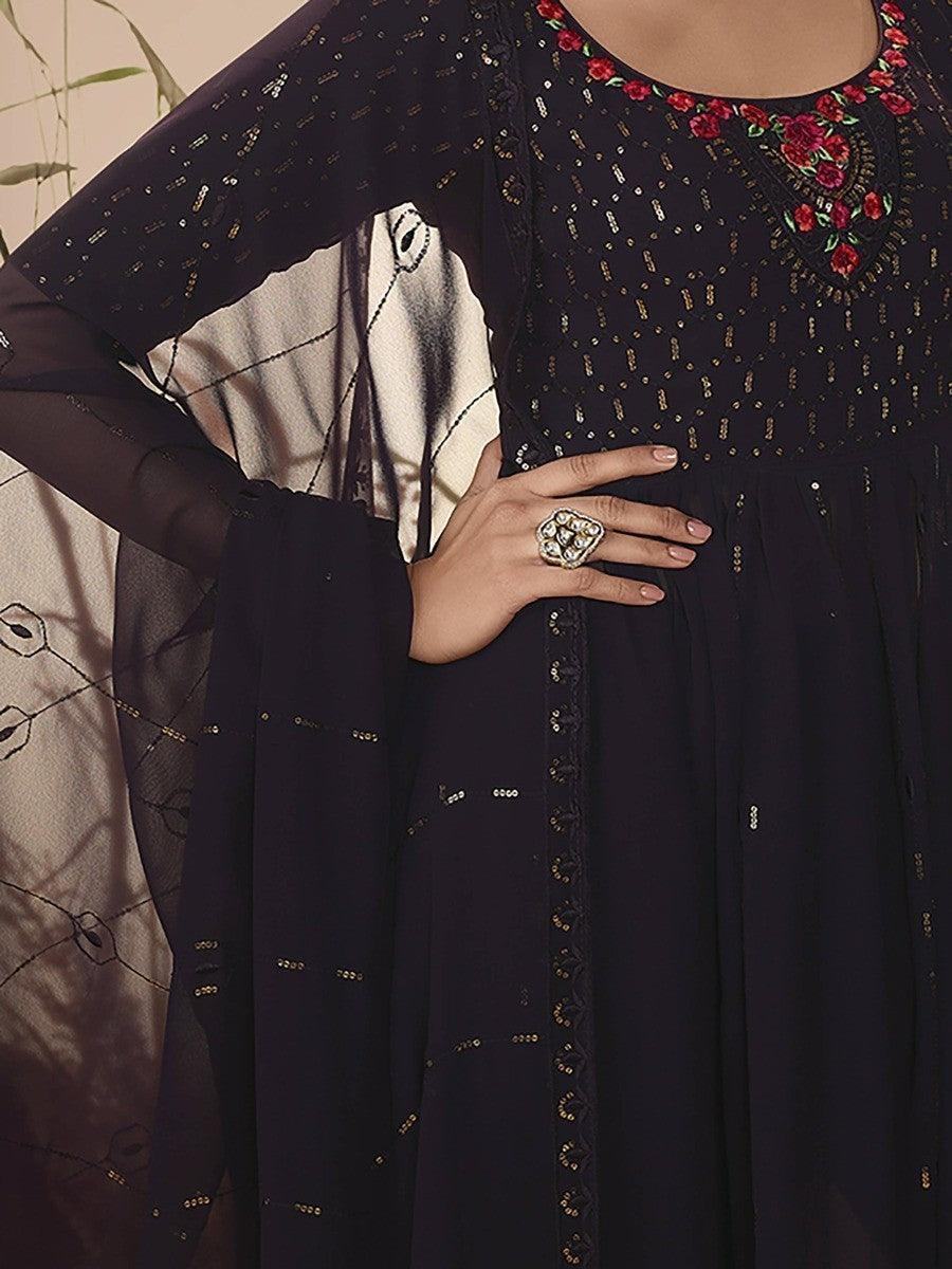 Elegant black embroidered dress with floral neckline and gold detailing, paired with statement ring