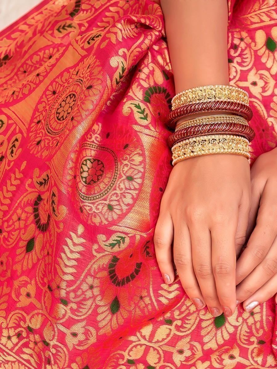Vibrant pink saree with gold paisley print and traditional bangles, perfect for festive occasions.