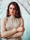 Elegant woman in beige embroidered long-sleeve top with gold jewelry, perfect for festive occasions.