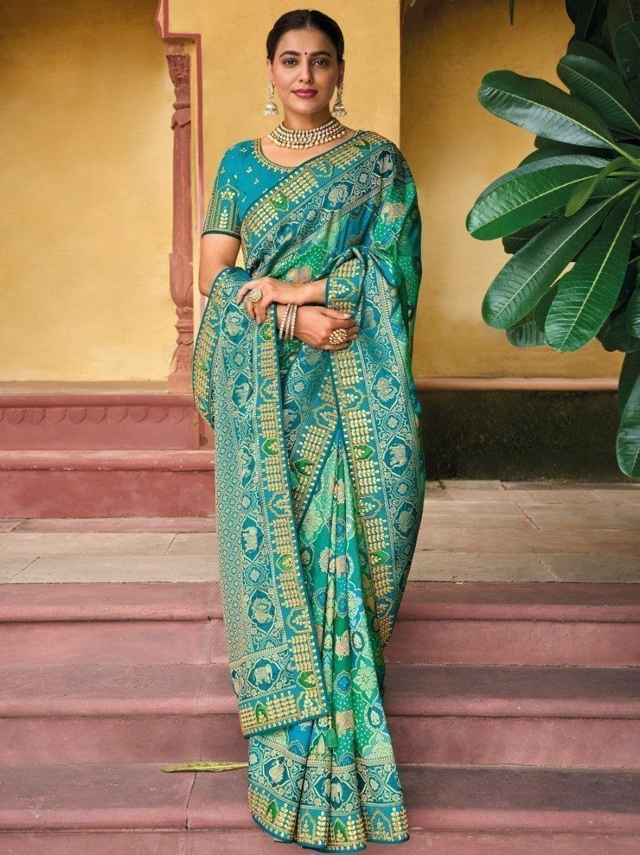 Woman in elegant teal and green printed saree with gold motifs, traditional Indian attire for festive occasions
