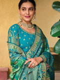 Woman in teal embroidered saree with gold detailing, traditional Indian fashion