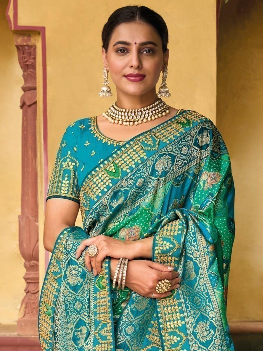 Woman in teal and green embroidered saree with gold jewelry, traditional Indian fashion