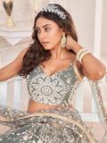 Woman in olive green embroidered lehenga with white floral patterns, matching blouse, and traditional jewelry