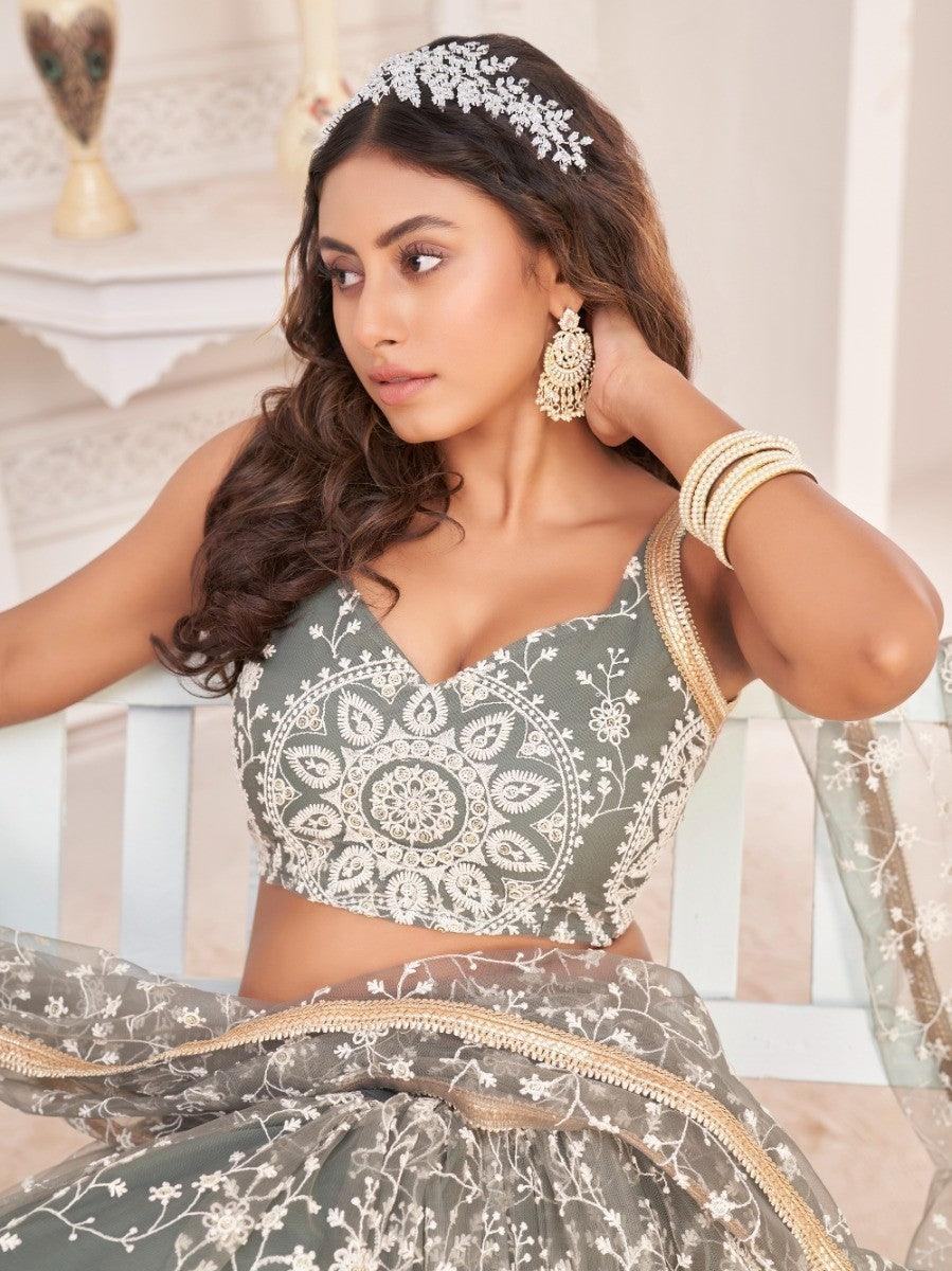 Woman in olive green embroidered lehenga with white floral patterns, matching blouse, and traditional jewelry