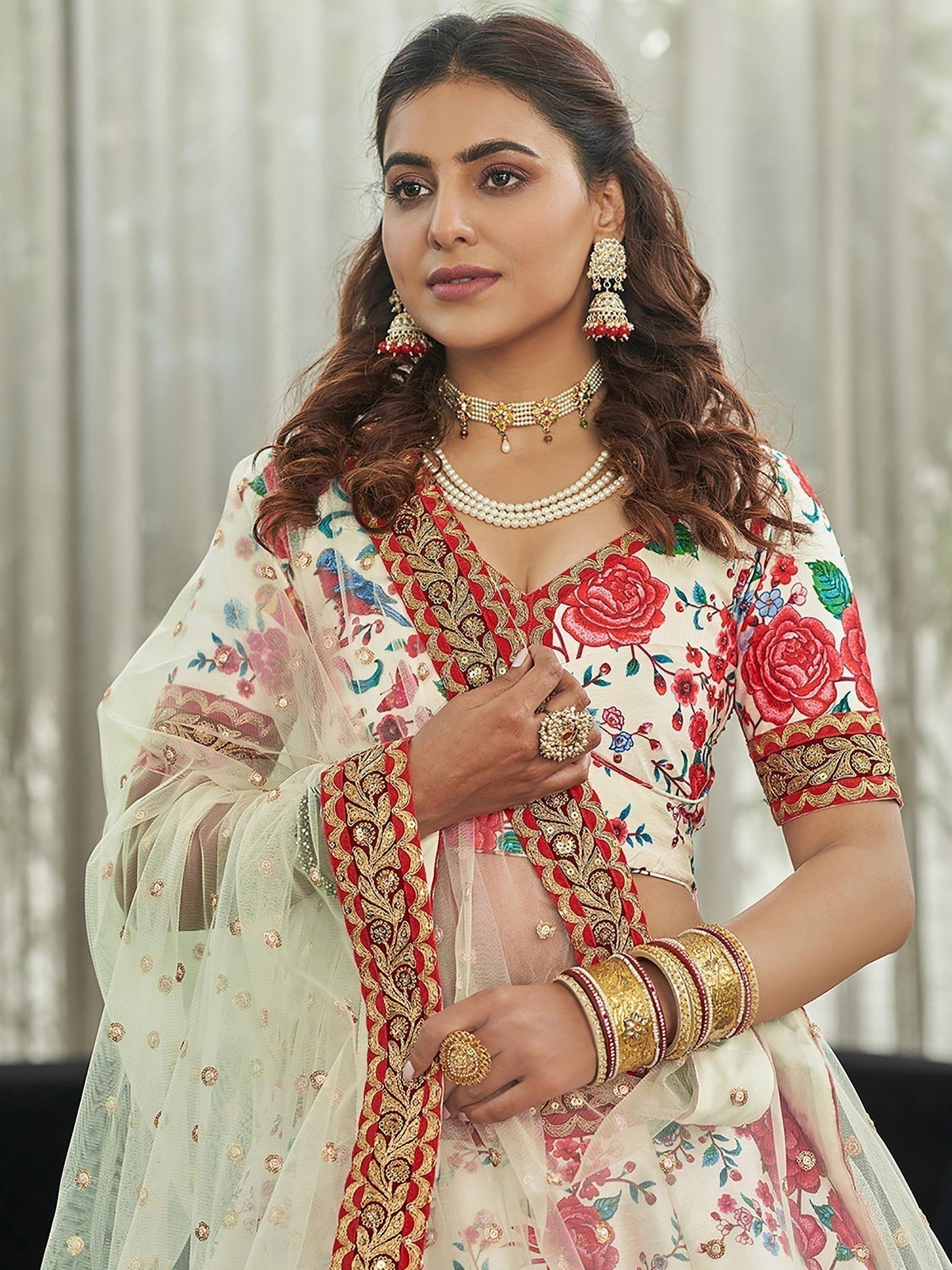 Woman in floral embroidered Indian suit with red gold detailing, pearl jewelry, and sheer dupatta