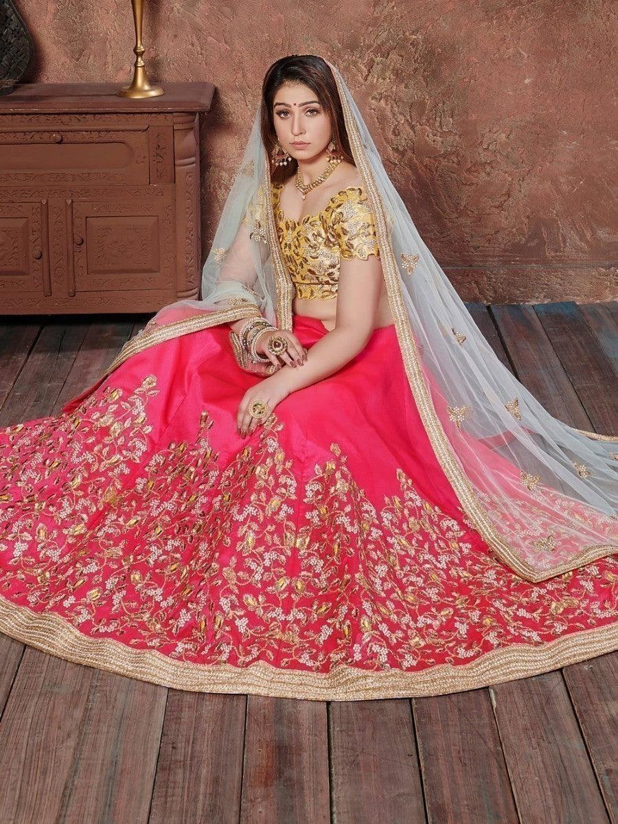 Woman in pink and gold embroidered lehenga with sheer dupatta, traditional Indian bridal wear